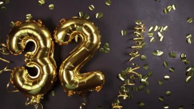 32 numaralı altın folyo balonu. Doğum günü ya da yıldönümü kartı 32 yazılıydı. Siyah beton arka plan. Yıldönümü kutlaması.