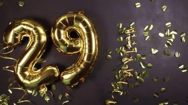 Globo de lámina dorada número 29. Tarjeta de felicitación de cumpleaños o aniversario con inscripción 29. Fondo de hormigón negro. Celebración del aniversario. — Vídeo de stock