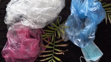 Kara toprakta bir sürü ev atığı, ıslak mendil, tıbbi maske ve daha fazlası var. Plastik bir küre çöp yığınına düşer. Dünya kirliliği kavramı.