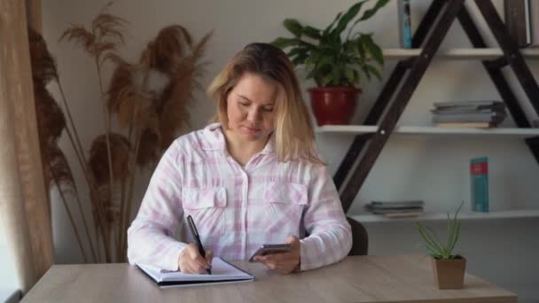 Manikürlü kadın yönetici ofiste akıllı telefona karşı dolma kalemle dolduruyor. İş kavramı. — Stok video