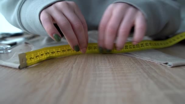 Närbild av en designerhand som mäter den mängd tyg som behövs med en flexibel tejp. designer i arbetsprocessen. Småföretagskoncept. — Stockvideo