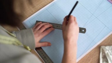 Kadın ellerinin üst görüntüsü yeni bir iç çamaşırı koleksiyonu çiziyor. Profesyonel bir tasarımcının işyeri. Boşluğu kopyala.