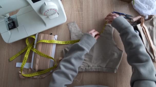 Ovanifrån på en designerhand som mäter den mängd tyg som krävs med en flexibel tejp. designer i arbetsprocessen. Småföretagskoncept. 4k — Stockvideo