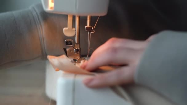 Seamstress mãos costurar roupas de tecido em uma máquina de costura. Mulher usando uma máquina de costura em casa. Uma mulher executa um ponto máquina lisa no tecido. Roupa artesanal, close up macro. — Vídeo de Stock