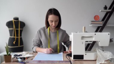 Genç beyaz kadın tasarımcı iç çamaşırları masaya oturur ve grafik kağıdına resim çizer. Yeni bir kıyafet koleksiyonu yarat. Küçük işletme konsepti. kopyalama alanı. metin için yer.