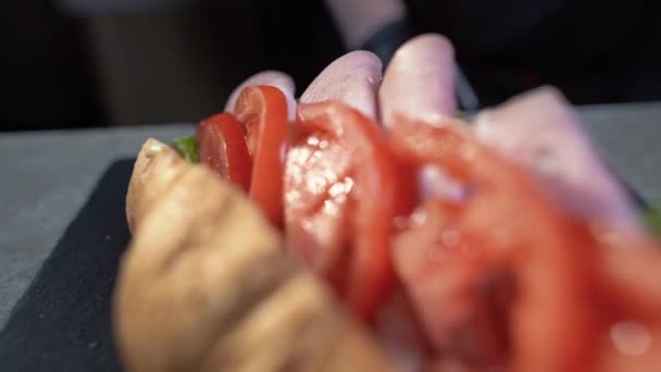 Primer plano de un delicioso y nutritivo sándwich con lechuga, tocino y tomate. Croissant para el desayuno. — Vídeo de stock