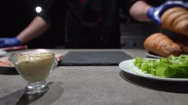 Les mains rapprochées du chef dans les gants coupent le croissant avec le couteau aiguisé. Pâtisseries appétissantes sur une planche à découper. Concept d'alimentation végétarienne saine. — Video