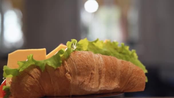 Delicioso croissant saludable con jamón, tomate y queso rotan sobre la mesa. Concepto de desayuno sándwich. — Vídeo de stock