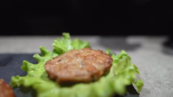 Proses membuat hamburger atau burger keju yang lezat. close-up chef tangan dalam sarung tangan menempatkan saus tomat merah pada cutlet goreng. — Stok Video