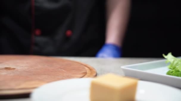 Les mains des chefs prennent une tomate mûre rouge et la mettent sur la planche à découper. La seconde main prend le couteau. Le concept de la cuisine salade de légumes. Mouvement de caméra. — Video