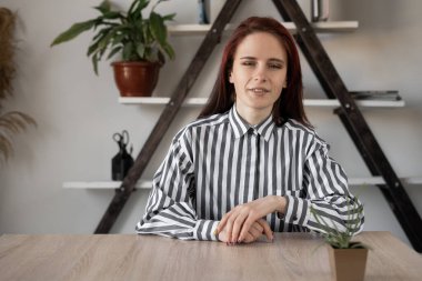 Masada oturan, kameraya bakıp konuşan beyaz bir kızın portresi. Çevrimiçi danışma.