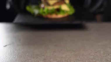 Şef masaya gelir ve lezzetli bir hamburger koyar, elleri siyah eldiven giyer. Besleyici bir kahvaltı..