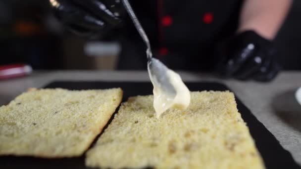 Het proces om focaccia te maken met kalkoenham in de keuken. De chefs handen brengen een grote laag witte saus of mayonaise met een lepel aan. — Stockvideo