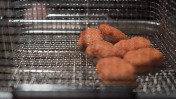 Cooking breaded fried chicken. Close-up of chicken nuggets in a deep fryer in a grid. 4k — Stock Video