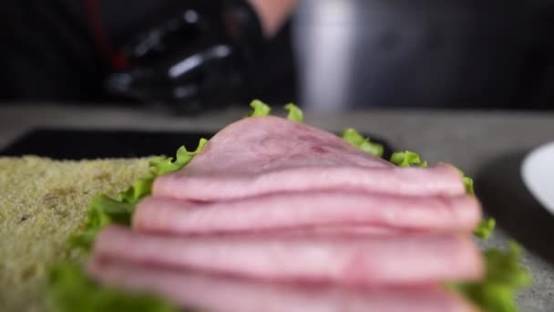 El proceso de fabricación de focaccia con jamón de pavo en la cocina. Los trozos delgados de la salchicha sobre la lechuga verde. — Vídeos de Stock