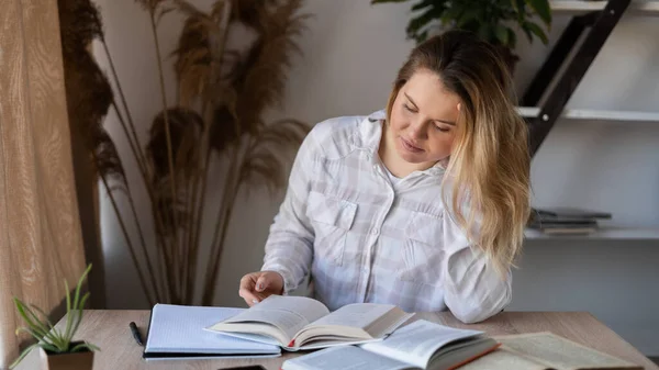 Προσωπογραφία Καυκάσου δασκάλου που κάθεται σε ξύλινο τραπέζι με βιβλία και βιβλία στο σπίτι δίπλα στο παράθυρο. Η γυναίκα ετοιμάζεται για το μάθημα. Διδασκαλία στο σπίτι. — Φωτογραφία Αρχείου