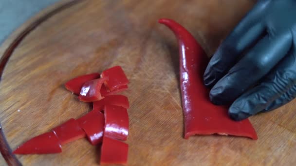 Primer plano de maestro culinario está cortando pimiento rojo para ser preparado como ingrediente de cocina en la cocina de restaurantes, corte pimiento rojo en una tabla de cortar blanco, 4K Filmación. — Vídeo de stock