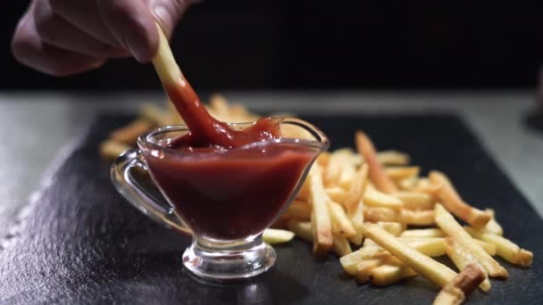 Męska ręka bierze ziemniaka i zanurza go w czerwonym sosie pomidorowym. Fast food. Spożycie żywności. — Wideo stockowe