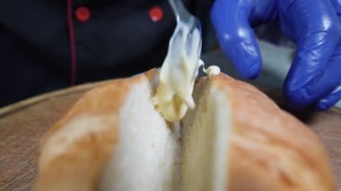 Şef kruvasan hazırlıyor. Bir kaşığın yakın çekimi çöreğe beyaz sos serpiştirir ve uygular..