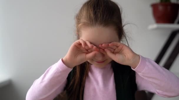 Piccola ragazza caucasica adolescente stanca 7-8 anni si siede e guarda contenuti video, strofina gli occhi con le mani. Problemi di vista. Il concetto di influenza della dipendenza da Internet sulla salute dei bambini — Video Stock