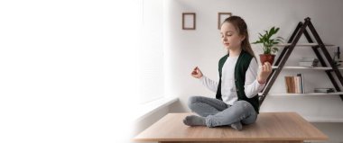 Lotus pozisyonunda, bacak bacak bacak üstüne atmış bir masada oturan küçük bir çocuğun meditasyonu ve rahatlaması. Öğrenci çevrimiçi derslerden ve ödevlerden sonra dinleniyor. Sağlıklı kız öğle yemeği molası.