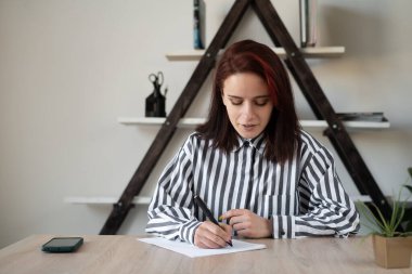 Çevrimiçi eğitim konsepti uzaklığı öğrenme milenyum yetişkin kızı masasında oturmuş ödev yapıyor. Çevrimiçi seminer veya konferans çalışmalarında bir öğrenci.