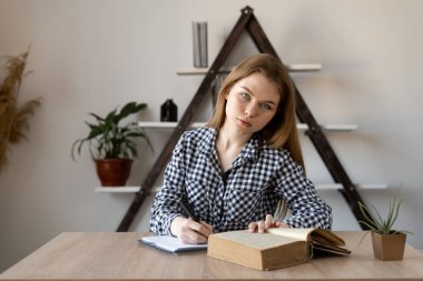 Uzaktan eğitim veren bir öğretmenle çevrimiçi öğrenci kız evdeki kameraya bakmadan notlar ve çalışmalar alıyor. Milenial bir internet serbest çalışanı..