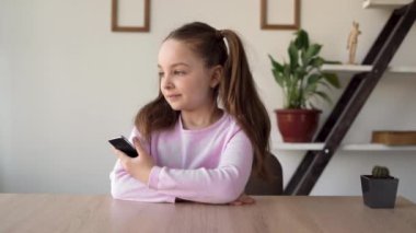 İnternete bağımlı bir kız elinde telefonla bir odada oturur ve sıkılır ve annesinden telefon bekler. Çocukların hayatlarındaki yetenekler ve çevrimiçi öğrenim sorunları.
