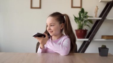 Akıllı beyaz kız, akıllı telefon ses asistanı kullanıyor ve ona cep telefonuyla sorular soruyor. Çocuklar için boş zaman. Genç bir bayan evde tek başına telefonla oynuyor..