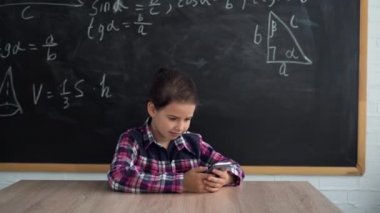 Okul konseptine geri dönelim. Liseli bir kız masada oturuyor ve akıllı telefonuna bir mesaj yazıyor. Boşluğu kopyala.