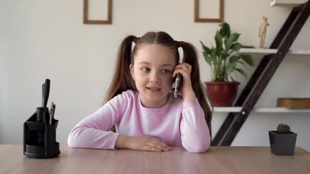 Uma garota emocional séria falando em um telefone celular escuta atentamente e alegremente se alegra e levanta as mãos. Crianças emoções positivas e um sorriso. Solidão em casa . — Vídeo de Stock