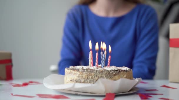 El primer plano de un pastel de cumpleaños festivo está sobre la mesa. Las velas están encendidas. La mujer pide un deseo y apaga las velas. fiesta concepto de fiesta. — Vídeo de stock