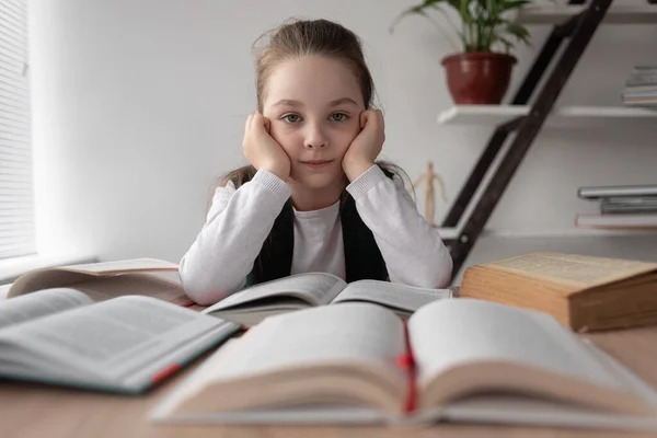 Gros plan d'une étudiante dans la classe assise à un bureau tenant sa tête avec ses mains. Une écolière qui a mal à la tête fait ses devoirs toute seule. Écoliers — Photo