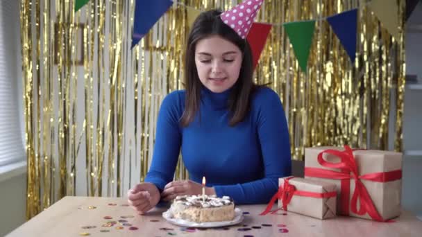 Mujer joven celebrando un cumpleaños se regocija y sopla la vela en el pastel de aniversario. Concepto de vacaciones. La dulzura es alegría femenina. Fiesta para una persona. — Vídeos de Stock