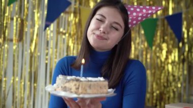 Yıldönümünü kutlayan bir pastayla bin yıllık yakın plan çekimleri şapka standındaki mumu söndürür ve tatlıyı zevkle kameraya gösterir. Uzak doğum günü.