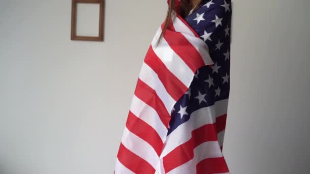 Молодая женщина и американский флаг 14 июня в комнате на кровати стоит и празднует День флага Америки людей патриотизм. Праздники США. День независимости Америки. — стоковое видео