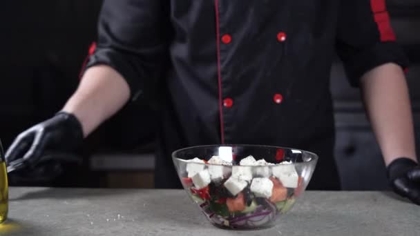 Primer plano de una mano de chefs con guantes negros. toma una cuchara y mezcla ensalada con cebolla, pepino y queso feta. — Vídeos de Stock