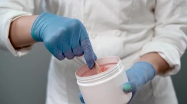 Kozmetikçi kavanozdaki şeker macununu alıyor. Shugaring. Konteynırdan bir spatula ile şeker ezmesi. Şekerleme için şeker ezmesi. Güzellik salonunda şekerleme.