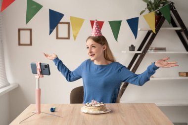 Bir kadın blogcu, ofisinde masanın üzerinde tripodla kameranın önünde otururken doğum gününü videoya kaydediyor. 25 yaşındaki bir kız evde bir partiyi kutluyor ve bir video kaydediyor.