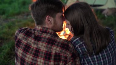 Bir adam ve bir kadın ateşin yanında gökyüzünün arka planına karşı öpüşüyorlar. Kamp yaparken, birbirini tutkuyla öpen bir çift....