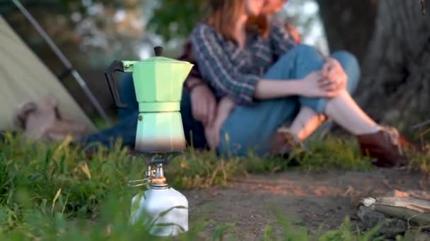 在徒步旅行或露营的时候，用煤气炉或野营的方式煮咖啡或茶壶- -背景是一对恋人相恋的青草- -旅行、自由和冒险的理念. — 图库视频影像