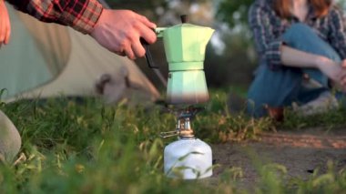 Ormandaki bir gaz ocağında çay ya da kahve yaparken bir adamın eli gayzer kahve makinesini çalıştırıyor. Açık havada yemek pişirme kampı. Turizm, açık hava eğlencesi ve kamp hayatı..