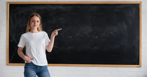 左の授業で黒板の近くに立っていた白人教師の少女の肖像画で、テキストの場所で指を指しています。学校に戻る。バナー — ストック写真