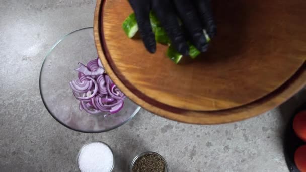 El proceso de preparación de ensalada griega para el menú del restaurante. Composición gastronómica de la cocina mediterránea en un estilo rústico. El chef puso el pepino en rodajas en un tazón con cebollas. — Vídeos de Stock