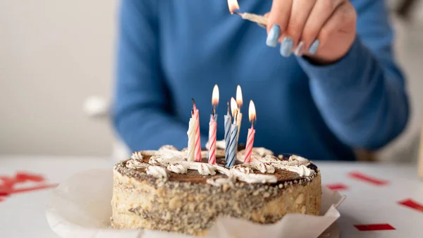 一个蛋糕的特写和一个女性的手点燃蜡烛。生日和甜糕点。周年蛋糕上的烛台. — 图库照片