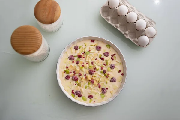 Surowy letni herbatnik z jagodami, malinami, jabłkami i cukrem dla wegetarian. Letnie jedzenie, letni tort w ceramicznym naczyniu do pieczenia. Gotowanie, surowe ciasto. — Zdjęcie stockowe