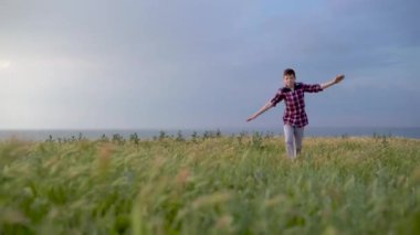 5 year old boy runs along the road in the field. Hands are spread apart. Dreams of flying. Place for your text.