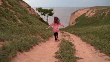 Küçük bir kız kollarını açar ve denize ya da okyanusa doğru yola koyulur. Özgürlük ve rahatlama kavramı. Çocuk dinleniyor..