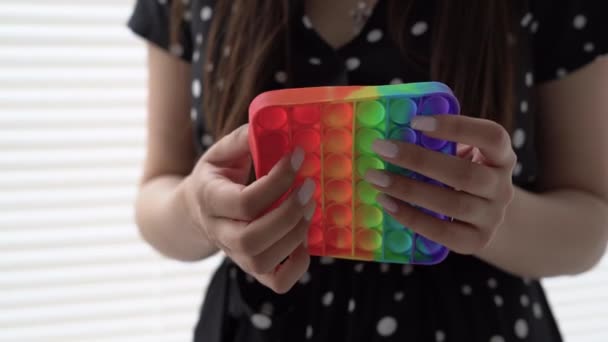 Close-up de mãos femininas segurando um brinquedo anti-stress e brincando com ele. Uma jovem sem rosto acalma seus nervos com um brinquedo infantil pop-lo. — Vídeo de Stock