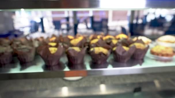 Det finns många muffins på displayen i snabbköpet. En kvinnlig hand tar en efterrätt. — Stockvideo
